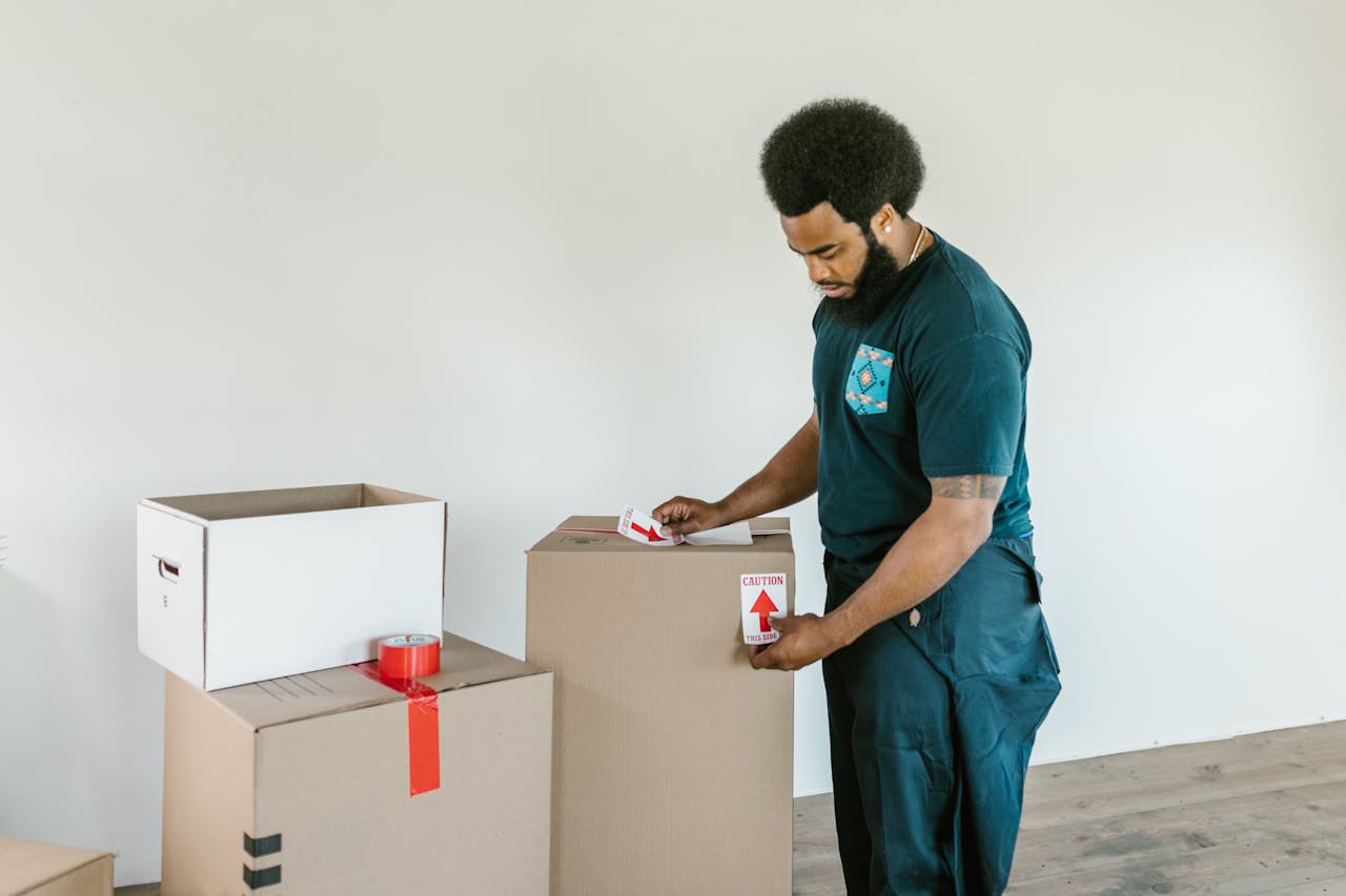 Man Putting Caution Stickers on Cardboard Boxes